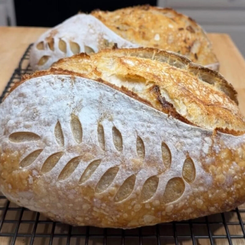 Classic sourdough loaf from Lone Star Bread Co., scored and dusted with flour, cooling on a wire rack.
